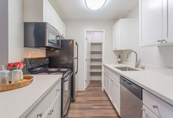 A kitchen with white cabinets and a black refrigerator